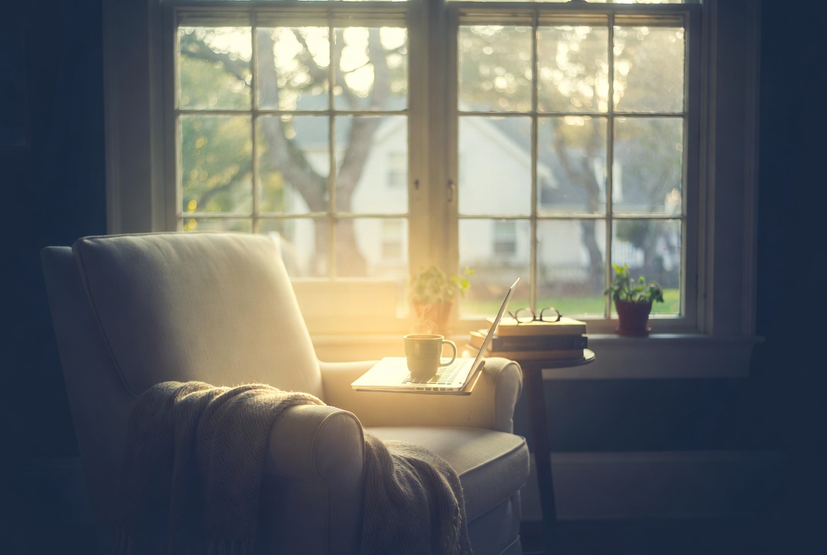 A warm New Jersey home interior set up for an online therapy session with Dr. Audrey Kteily — laptop open, comfortable chair, golden afternoon light